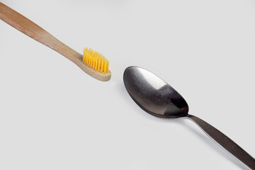 Wooden tooth brush and a spoon diagonally on white background