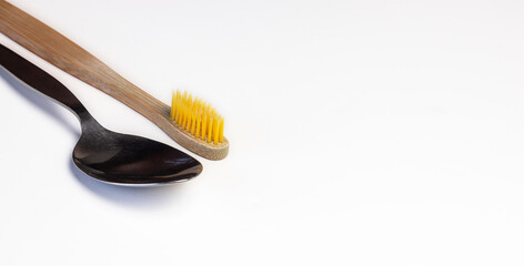 Wooden tooth brush and a spoon diagonally together on white background