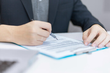 Business partners concept a young businessman holding a pen pointing at profit summary of the recent month showing in document forms