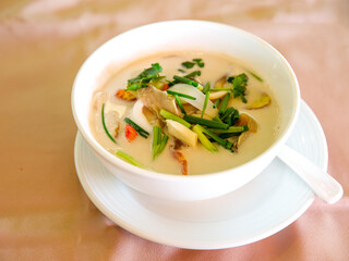 Thai shrimp sour and spicy soup in creamy coconut milk or Tom Kha Kung, famous traditional Thai food in white ceramic bowl, top view