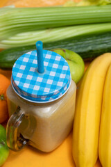 Freshly prepared smoothie in jar with tube close-up. Nearby there is celery, banana, apple. Selective focus.