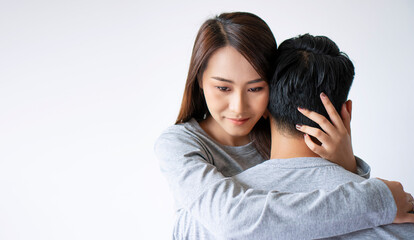 Upset Asian wife embracing husband misunderstanding infidelity on white background. Sad Asian...
