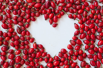 Rose-hips, spread on a table, seen from above, with a blank, heart-shape space in the middle