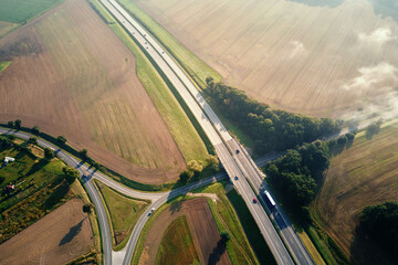 Highway crossroad with moving cars and trucks, aerial view. Asphalt road through countryside landscape