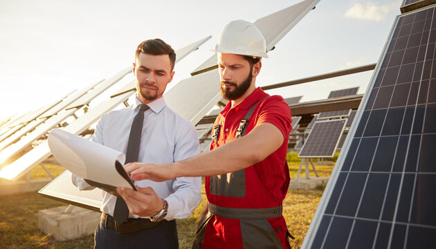 Contractor and manager working in field with solar panels