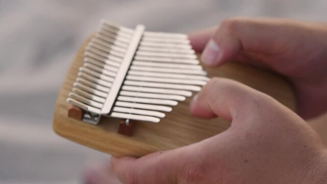 Closeup hands holding and play Kalimba Mbira or thumb piano. African musical instrument. Kalimba made from wooden board with metal, play on hands and plucking tunes with thumbs. selective focus