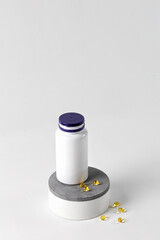Bottle with vitamins D on podium. Pills or drugs on white table. Yellow pills. Mock up. Immune system