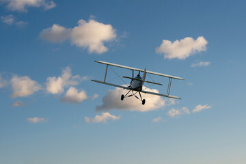 Fototapeta na wymiar biplane plane in the blue sky with white clouds