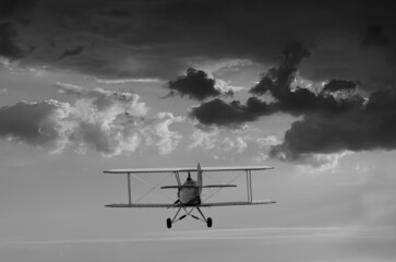 biplane plane flies in cloudy sky - impending storm