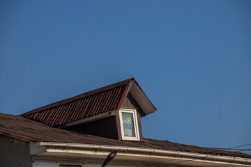 The roof of the house is made of red metal tiles, a beautiful large chimney