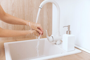 Washing hands under the flowing water tap. Hygiene concept hand detail. Washing hands rubbing with soap for corona virus prevention, hygiene to stop spreading corona virus in or public wash room.