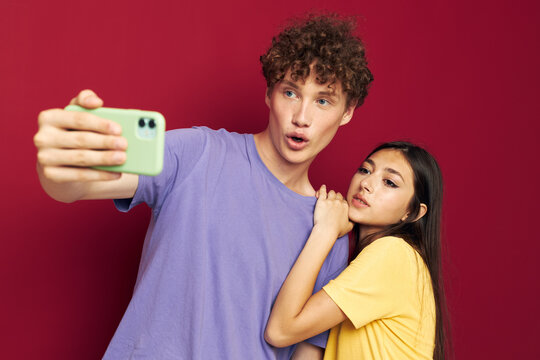 nice guy and girl in colorful T-shirts with a phone red background