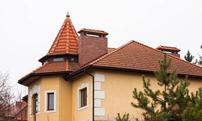 The roof of the house is made of red metal tiles, a beautiful large chimney