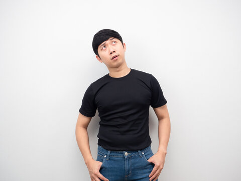 Asian man with jeans looking up at copy space