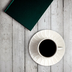 Book and cup of coffee on a wooden background. Top view, flat lay. The concept of home relaxation, tea drinking.