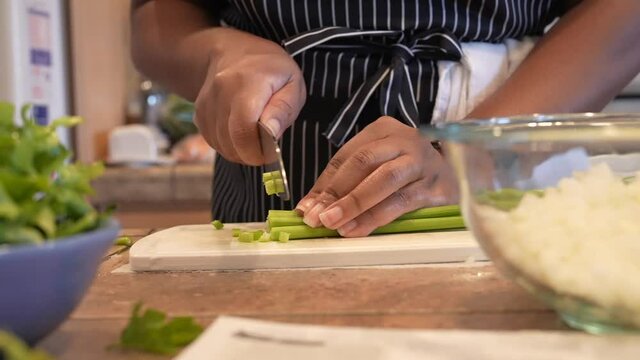Chopping fresh organic celery for a homemade recipe - side view in slow motion