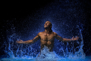 Muscular man in water under the rain