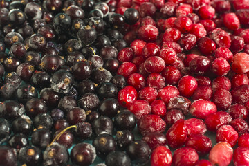 Texture of a mixture of red and black frozen berries in close-up.