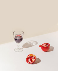 Creative composition made of glass of red wine or juice and pomegranates on pastel  backgound with...