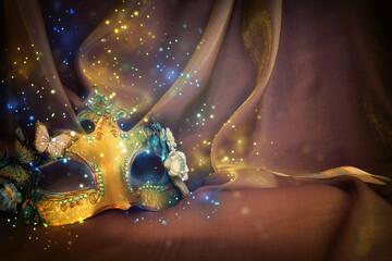 Photo of elegant and delicate Venetian mask over gold silk background