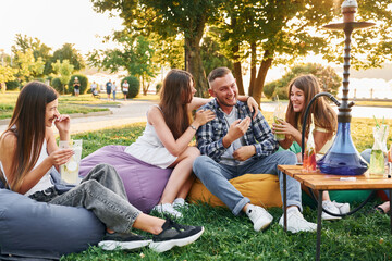 In casual clothes. Group of young people have a party in the park at summer daytime