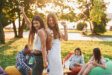 Standing and having fun. Group of young people have a party in the park at summer daytime