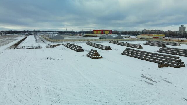 Flying over a snowy field. Straw bales are stacked. Traces of agricultural tillage are visible under the snow. Aerial photography.