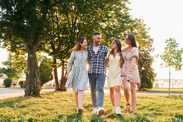 Man with three women standing in the park and embracing