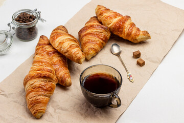 Croissants and  cup of coffee on paper.  Jar with coffee grains.
