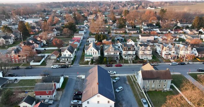 Aerial truck shot of small town USA in winter sunrise. Car drives on street through community neighborhood. Establishing shot.