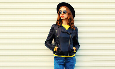 Fashionable portrait of stylish young woman model posing wearing a black rock style jacket on white background