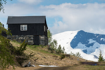 Fototapeta na wymiar Dark hut with mountains with glacier in background.