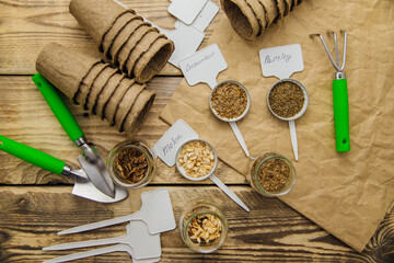Top view of seeds and garden tools on a wooden background. Growing seedlings using peat cups.