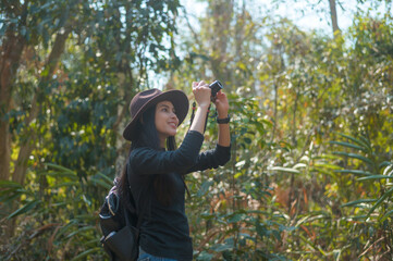 Young woman trekker taking photos of nature with camera in the woods, holidays and traveling concept.