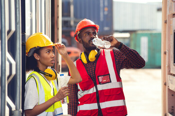 Man and woman american african technician drinking water and resting after working at container yard. - Powered by Adobe