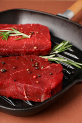 Concept of cooking with raw beef steaks on brown background