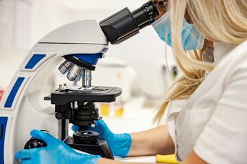 Microbiology and science. A nurse is sitting in the laboratory and using a microscope for a new...