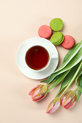 Tea, tulips and macaroons on beige background