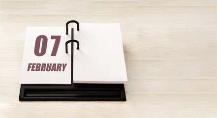 february 7. 7th day of month, calendar date.  Stand for desktop calendar on beige wooden background. Concept of day of year, time planner, winter month