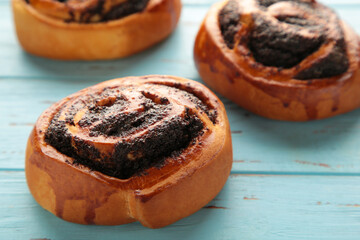 Bun with poppy seeds on blue wooden background.