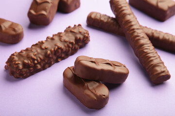 Mix of chocolate bars on purple background with copy space. Top view.