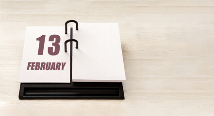 february 13. 13th day of month, calendar date.  Stand for desktop calendar on beige wooden background. Concept of day of year, time planner, winter month