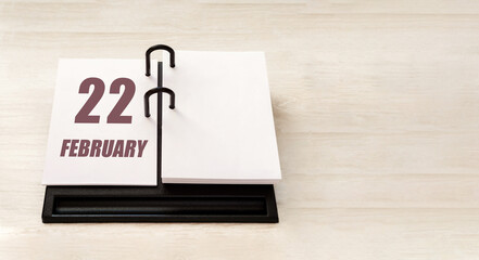 february 22. 22th day of month, calendar date.  Stand for desktop calendar on beige wooden background. Concept of day of year, time planner, winter month