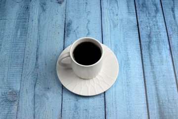 Cup with coffee on a saucer on a blue wooden background. Top view, flat lay. The concept of relaxation, rest, tea drinking.