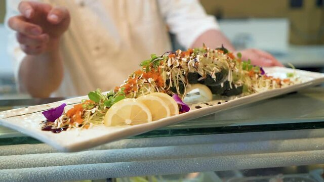 Sushi chef places prepared roll on bar, extravagant sushi maki roll, beauty shot, HD