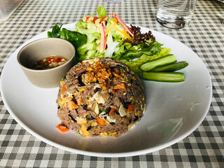 Dish of Salmon fried rice served with vegetable salad and fish sauce with chilli in Thailand.
