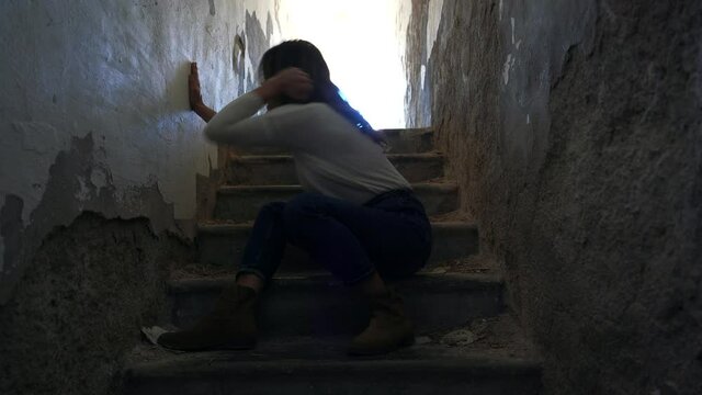 desperate caucasian woman girl cries sitting on the ground in a dark environment after being raped - sexual abuse against women 