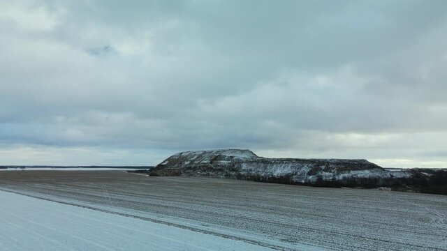 Flying over a snowy field. The city dump is visible, covered with snow. Mothballed waste landfill. Aerial photography.