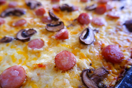 チーズをたっぷりのせたソーセージとキノコのピザ