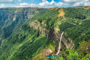 waterfall streams falling from mountain top covered with green forests at day